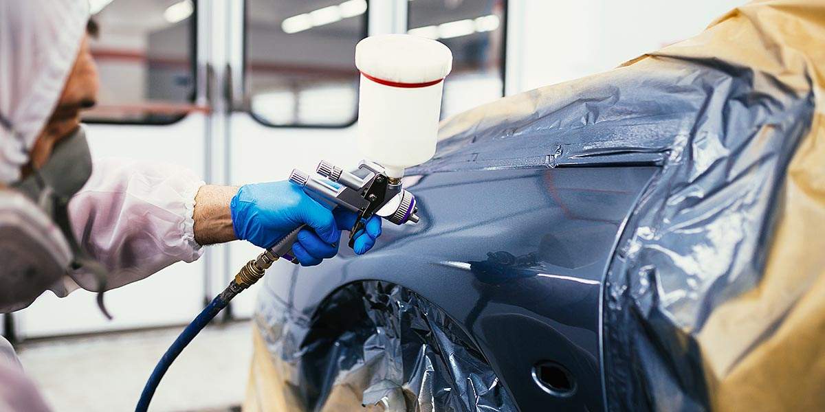 Autoteile werden mit Spritzpistole lackiert